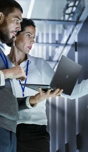 two colleagues discussing work while holding a laptop